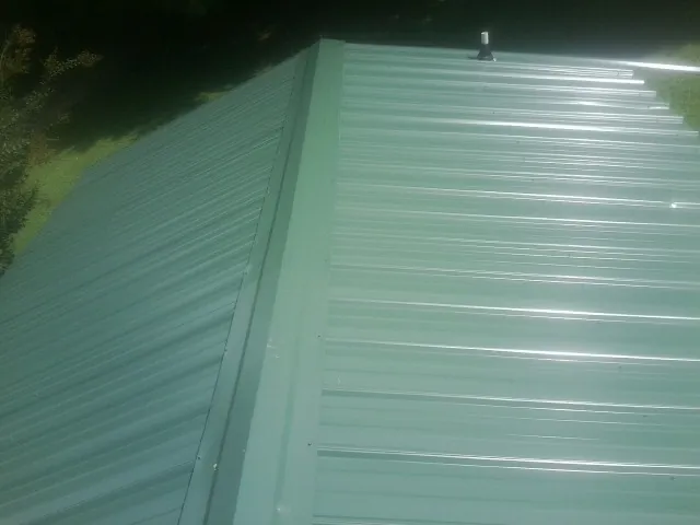 New green metal panels meeting at the ridge of a roof — Flat Roof Repair work by our crew in Stanwood