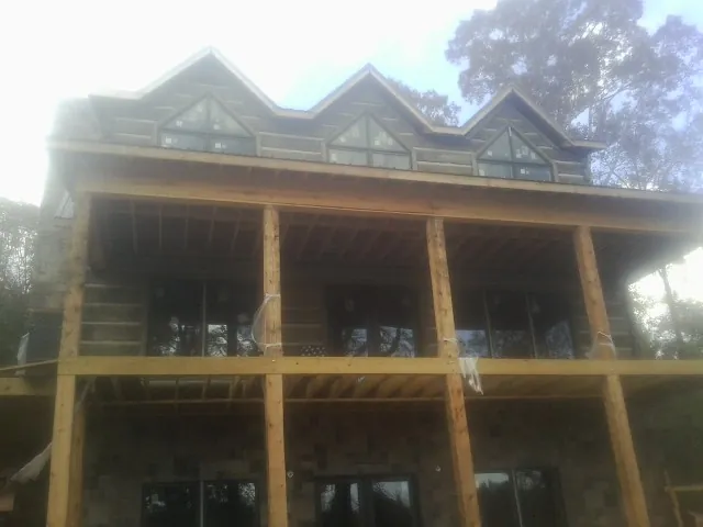 Dormers and porch framing on a large log home under construction — Roof Coating work by our crew in Stanwood