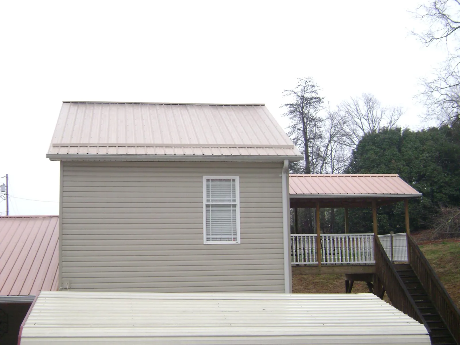 Tan metal roofs on a two story addition and attached porch, from a Roof Replacement job in Stanwood
