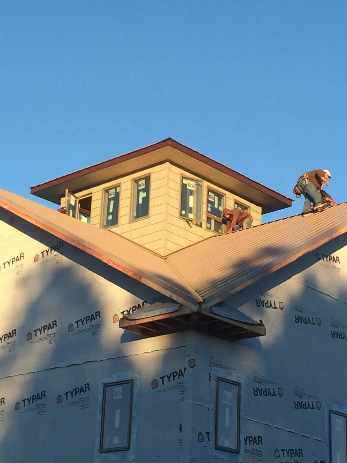 Roofers working around a rooftop cupola on a new metal roof at sunset — Roof Waterproofing in Stanwood by Roofing Brothers
